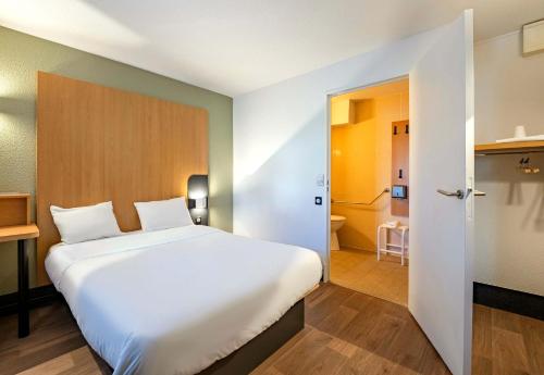 a bedroom with a large white bed and a bathroom at B&B HOTEL Saint-Etienne La Terrasse in Villars