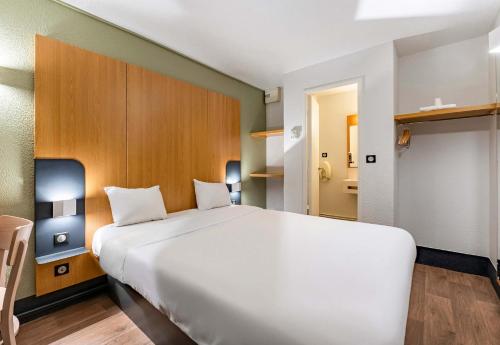 Cette chambre comprend un grand lit blanc. dans l'établissement B&B HOTEL Saint-Etienne La Terrasse, à Villars