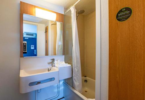 La salle de bains est pourvue d'un lavabo et d'un miroir. dans l'établissement B&B HOTEL Saint-Etienne La Terrasse, à Villars