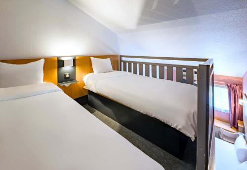 a bedroom with two beds and a window at B&B HOTEL Saint-Etienne La Terrasse in Saint-Étienne