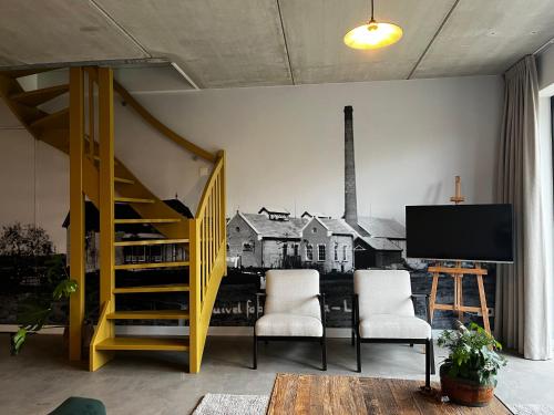 a living room with two chairs and a tv on a wall at Gastenverblijf 'tsiishokje' in Lioessens