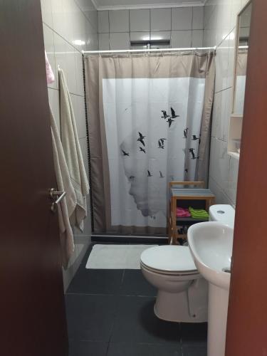 a bathroom with a toilet and a shower curtain with birds at Wavecrest in Horta
