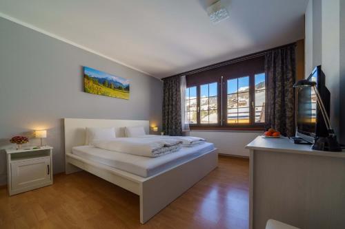 a bedroom with a bed and a desk with a television at Hotel Toggenburg in Wildhaus