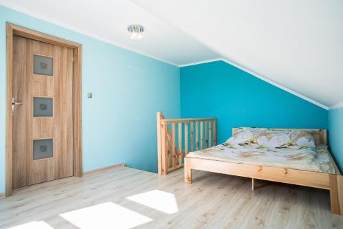 a bedroom with blue walls and a wooden door at Agroturystyka Golubie in Ełk