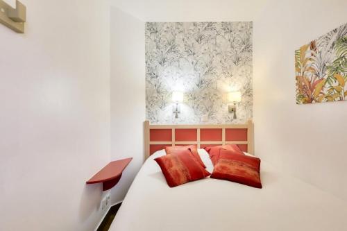 une chambre avec un lit blanc avec des oreillers rouges dans l'établissement Résidence le Village de Cap Esterel - maeva Home - Appartement 2 Pièces 4 Personnes - Sélection MAE-3114, à Saint-Raphaël