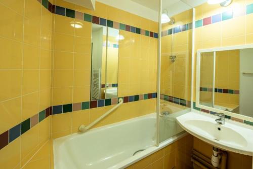 y baño con bañera, lavabo y espejo. en Résidence Les Terrasses d'Arcangues - maeva Home - Studio 5 Personnes - Budget, en Arcangues