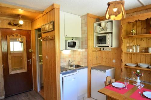 une cuisine avec des armoires en bois, un évier et une table dans l'établissement Résidence Tougnette - Studio équipé ski aux pieds aux Ménuires MAE-4004, aux Menuires