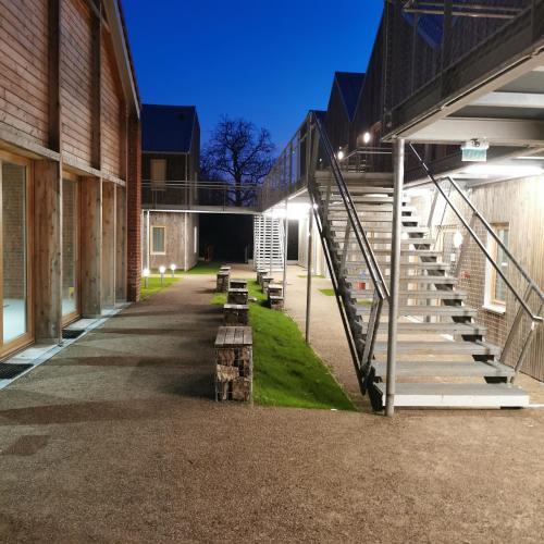 a row of benches in an alley between two buildings at La Ferme Des Ailleurs in Arleux-du-Nord