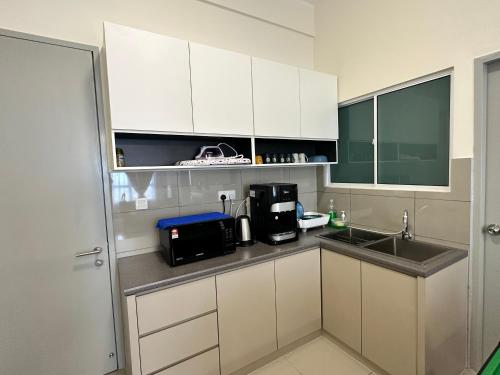 a kitchen with white cabinets and a sink at Amber Cove Seaview I MUJI 2BR I Game Room I 3-9pax in Malacca