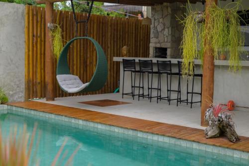 a swimming pool with a chair next to a bar at Villa Meraki in Pipa