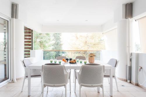 una sala da pranzo bianca con tavolo e sedie bianchi di Elegant Maisonette 4BD Glyfada ad Atene