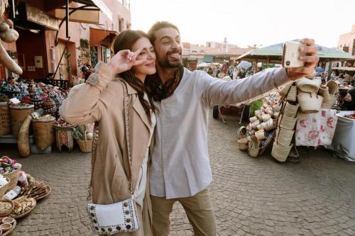 a man and a woman taking a picture at a market at Ibis Marrakech Centre Gare in Marrakech