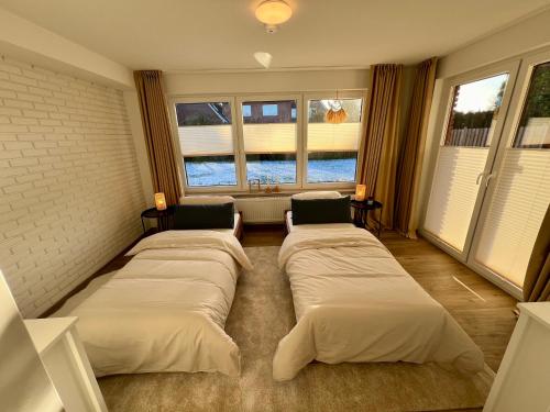 a bedroom with three beds in a room with windows at Appartement „Zum Weißen Hahn“ in Bad Zwischenahn