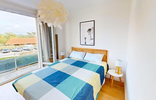 ein Schlafzimmer mit einem Bett und einem großen Fenster in der Unterkunft Sable - Appartement rénové pour 4 personnes in Soorts-Hossegor