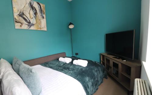 a bedroom with a bed and a flat screen tv at The Windsor Club Apartment in Leamington Spa