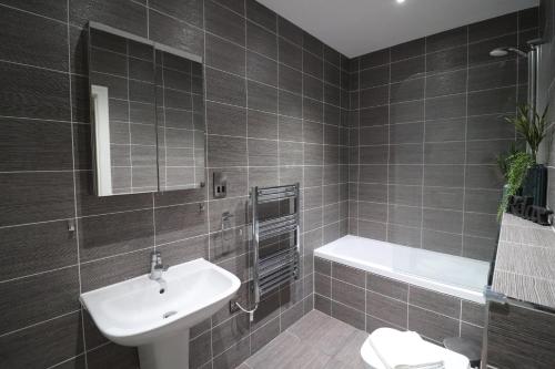 a bathroom with a sink and a toilet and a tub at The Windsor Club Apartment in Leamington Spa