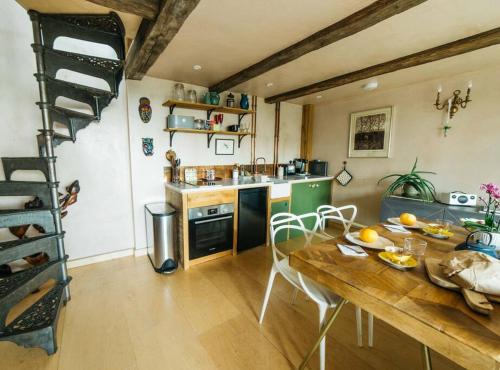 a kitchen with a wooden table and a kitchen with a ladder at Romantic Country Annex With Views - 10 min to Bath in Cold Ashton