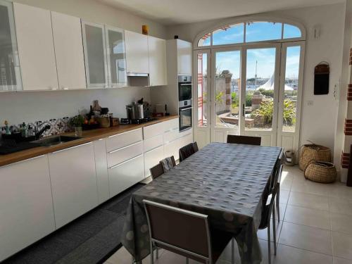une cuisine avec une table et des chaises ainsi qu'une grande fenêtre dans l'établissement Pornichétine pour 8 personnes face à l'océan et à 100m du marché, à Pornichet