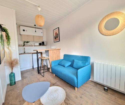 a living room with a blue couch and a kitchen at Cocon cosy au cœur de Verneuil in Verneuil d’Avre et d’Iton