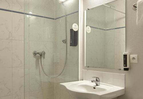 a bathroom with a shower and a sink and a mirror at B&B HOTEL Saclay in Saclay