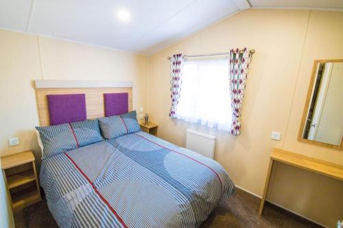 a bedroom with a bed and a window at SP150 - Camber Sands Holiday Park - Sleeps 8 - 3 Bedrooms - En-suite - Decking - Private Parking in Camber