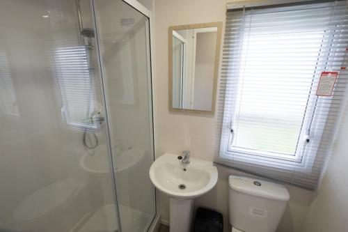 a bathroom with a shower and a toilet and a sink at SP158 - Camber Sands Holiday Park - 3 Bedrooms - Second Toilet - Decking - Private Parking in Camber