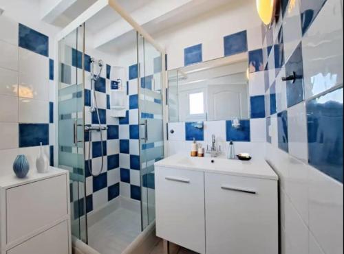 La salle de bains bleue et blanche est pourvue d'un lavabo et d'une douche. dans l'établissement Appartement face à la mer - Saintes-Maries-de-la-Mer, à Saintes-Maries-de-la-Mer