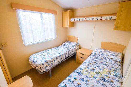 a small room with two beds and a window at WW165 - Camber Sands Holiday Park - Sleeps 6 - 2 Bedrooms - 2 Bathrooms in Camber