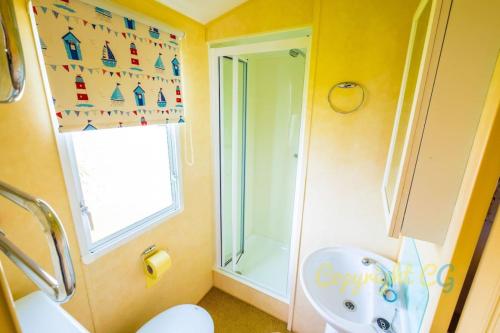 een badkamer met een wastafel, een toilet en een raam bij WW165 - Camber Sands Holiday Park - Sleeps 6 - 2 Bedrooms - 2 Bathrooms in Camber