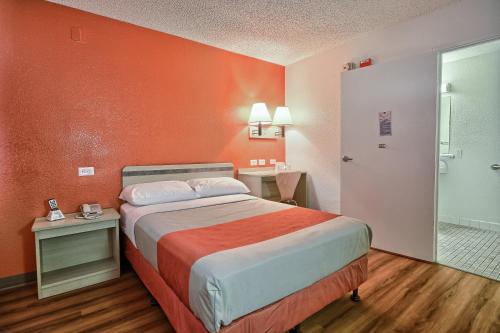 a hotel room with a bed with an orange wall at Motel 6-Fresno, CA - Blackstone South in Fresno