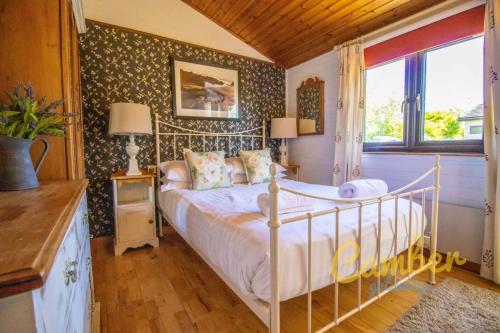 1 dormitorio con cama y ventana en Five Waterings - Luxury Lodge en Brookland