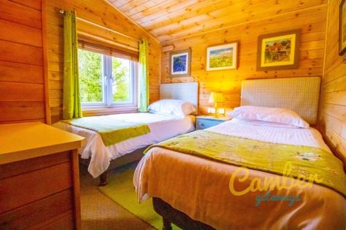 a bedroom with two beds in a wooden cabin at Rainbow Petty - Pine lodge - Kent countryside in Brookland