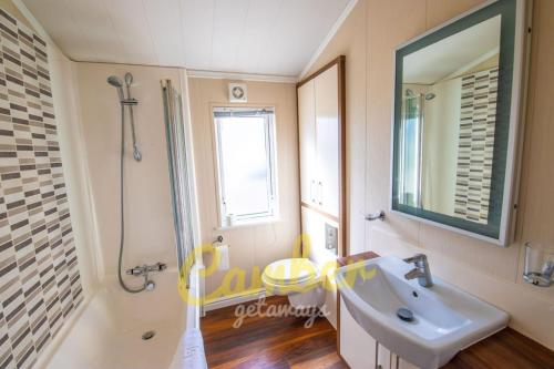 W łazience znajduje się umywalka, prysznic i lustro. w obiekcie MP768 - Camber Sands Holiday Park - Huge Lodge - Small dog friendly - sleeps 8 w mieście Camber