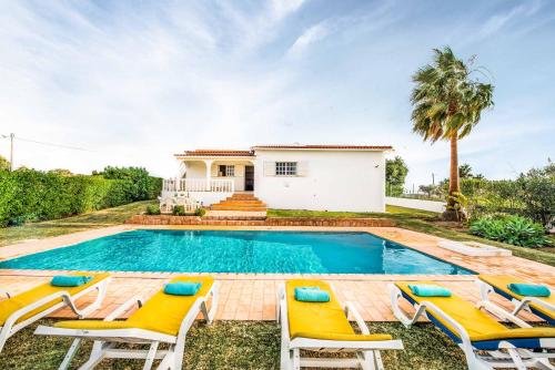 a swimming pool with chairs and a house at Villa Barrancos in Guia