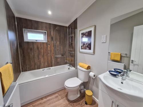 a bathroom with a toilet and a tub and a sink at Puddledock - luxury lodge - Kent countryside in Brookland