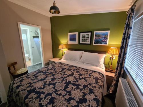 ein Schlafzimmer mit einem Bett und einer grünen Wand in der Unterkunft Puddledock - luxury lodge - Kent countryside in Brookland