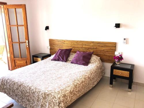 1 dormitorio con 1 cama grande con almohadas moradas en Villa Roferos 32, en Puerto del Carmen