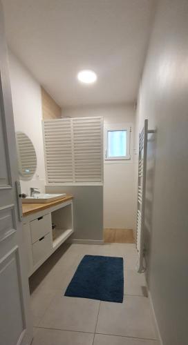 La salle de bains est pourvue d'un lavabo et d'un tapis bleu. dans l'établissement Goratcho, à Ciboure