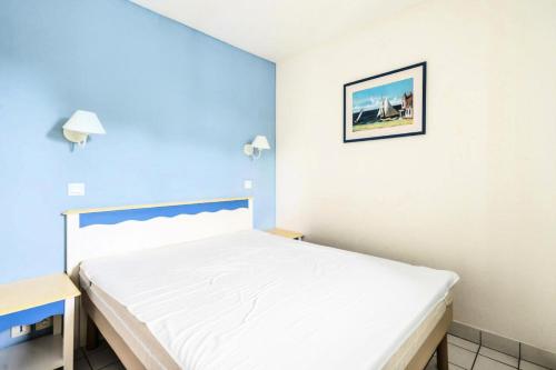 - une chambre avec un lit blanc et un mur bleu dans l'établissement Port du Crouesty Cap'Océan - maeva Home - 2 pièces 5 personnes - Confort - vue sur le Port MAE-1334, à Arzon