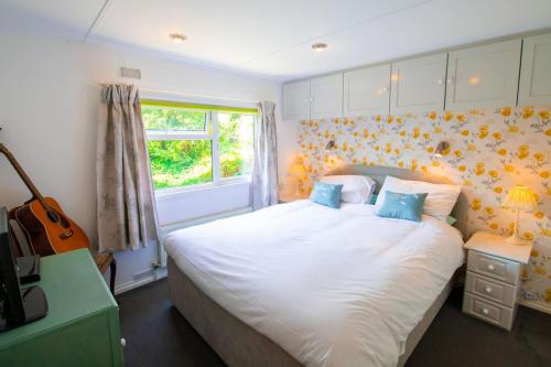 um quarto com uma grande cama branca com almofadas azuis em 11 The Oaks - Lodge - Coghurst Hall - Hastings em Westfield