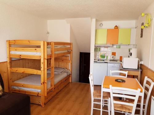 Cette chambre comprend des lits superposés, une table et une cuisine. dans l'établissement Résidence Challe - Joli studio 4 personnes ski au pied et vue sur les pistes. MAE-4254, aux Menuires