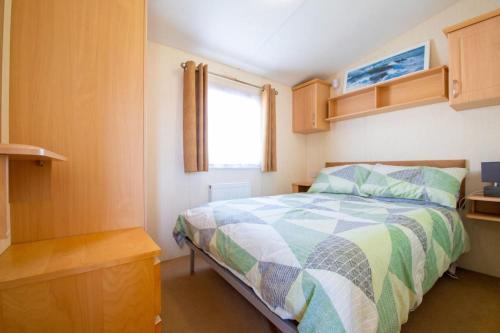 um pequeno quarto com uma cama e uma janela em WW213 - 4B - Parkdean Resorts - Camber Sands - Com em Camber