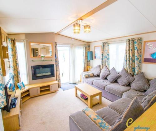a living room with a couch and a tv at MP639 - Camber Sands Holiday Park - 3 Bedroom - Sleeps 8 - Large gated decking - Close to facilities in Camber