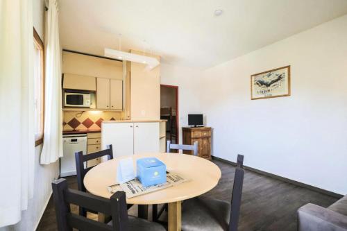 une cuisine et une salle à manger avec une table et des chaises dans l'établissement Résidence Les Ravines - maeva Home - Studio 4 personnes Sélection MAE-3344, à Les Allues