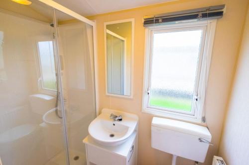 a bathroom with a sink and a toilet and a window at MP694 - Camber Sands - Sleeps 8 in Camber