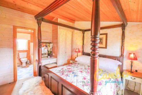Dormitorio con cama con dosel en una cabaña en Tore Petty - Romantic lodge - spa bath and sauna, en Brookland