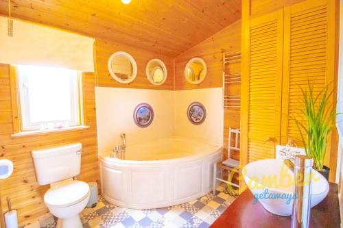 y baño con bañera, aseo y lavamanos. en Tore Petty - Romantic lodge - spa bath and sauna, en Brookland