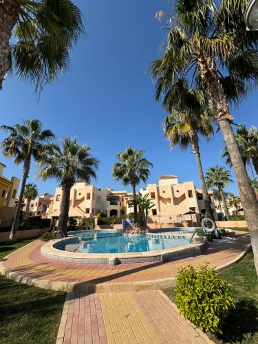 una piscina en un complejo con palmeras en Bungalow Punta Marina, en Torrevieja