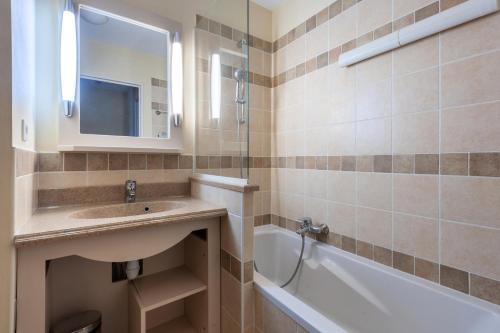 ein Badezimmer mit einem Waschbecken, einer Badewanne und einem Spiegel in der Unterkunft Les Coteaux de Pont Royal en Provence - maeva Home - Maison 3 Pièces 6 Pers 944 in Mallemort