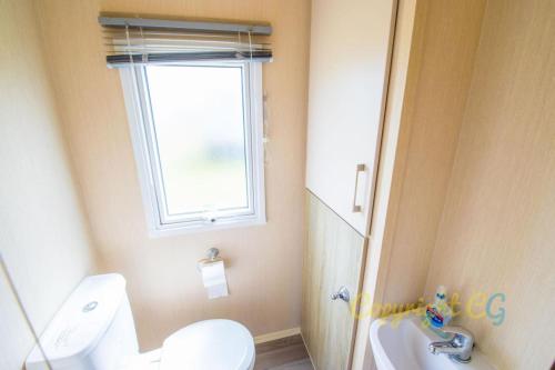 a bathroom with a toilet and a window and a sink at SP84 - Camber Sands Holiday Park - 3 Bedroom - Sleeps 8 - Private Parking in Camber
